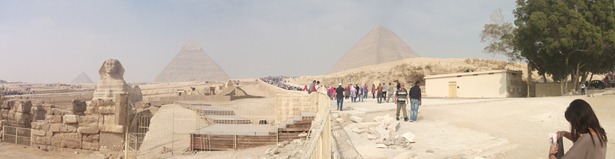A wide shot from the bottom of Giza Plateau in which you can see the Sphinx and all three of the pyramids