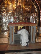 Thomas kneeling at the altar above the stone of Golgotha